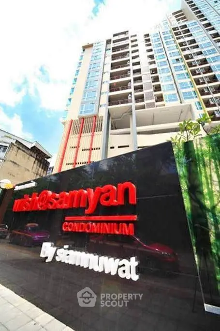 Modern condominium building exterior with prominent signage and clear blue sky.