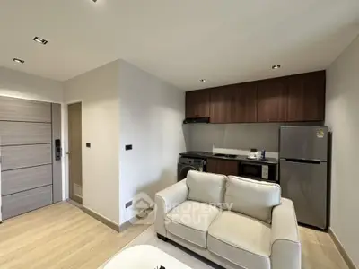 Modern living room with compact kitchen featuring sleek appliances and cozy seating area.