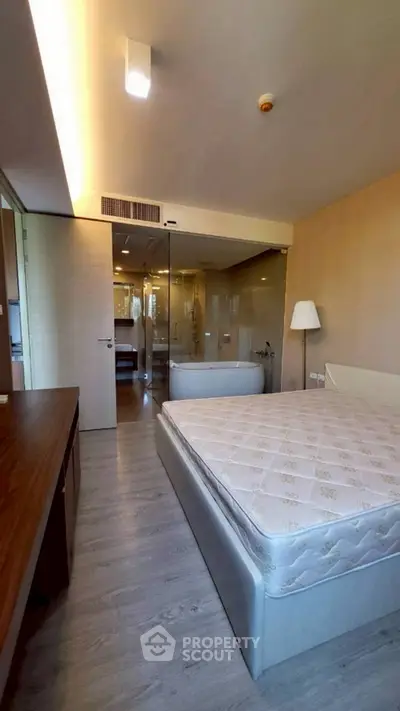 Modern bedroom with glass-walled bathroom and elegant furnishings