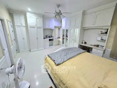 Spacious bedroom with elegant white cabinetry and ceiling fan