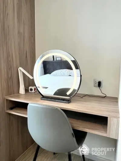 Modern study area with sleek desk, stylish chair, and illuminated mirror in contemporary apartment.