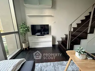 Modern living room with staircase, large window, and stylish decor in urban apartment.