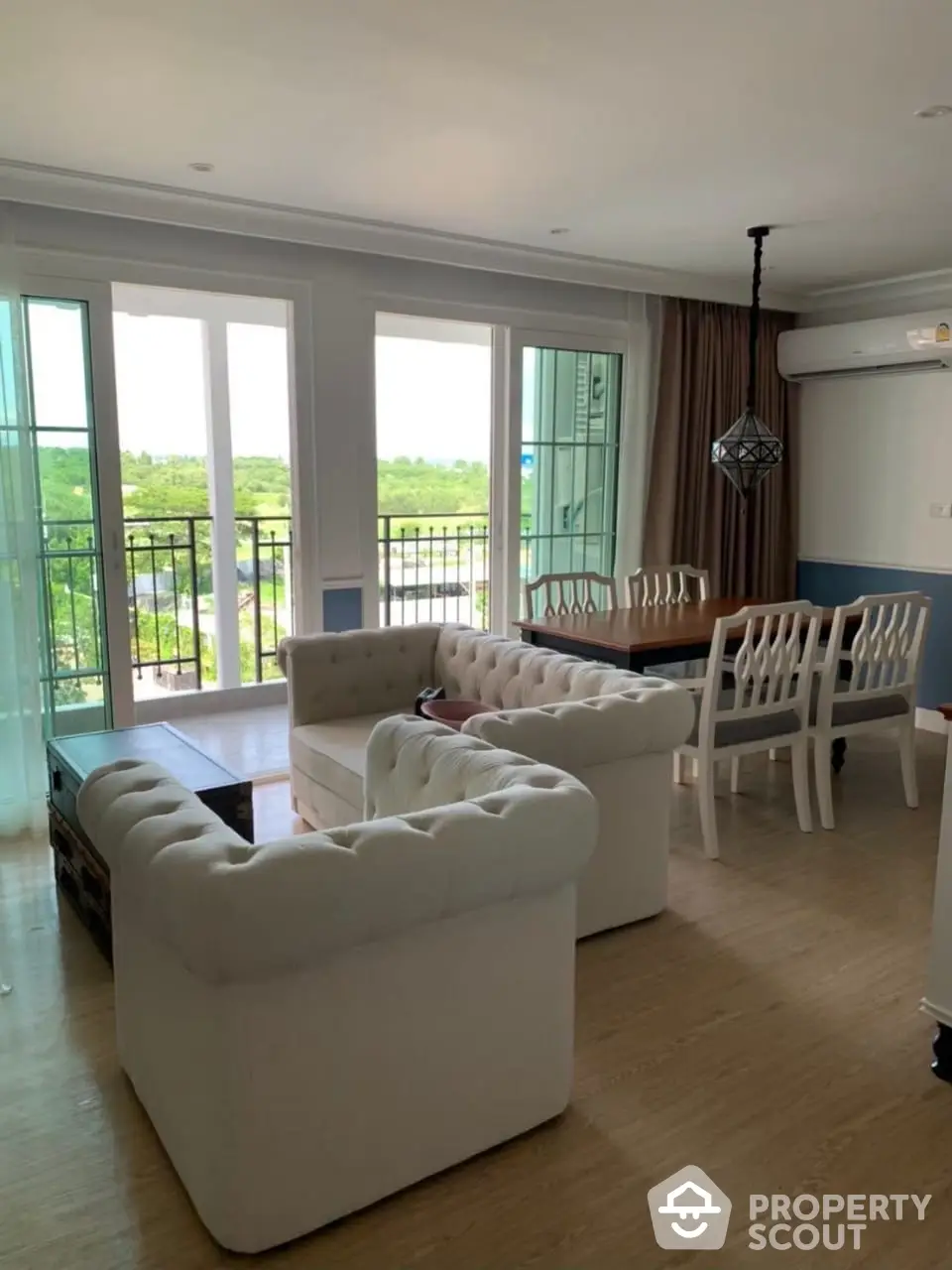 Spacious living room with plush sofas, elegant dining set, and panoramic windows offering an unobstructed serene view, perfect for entertaining and relaxation.