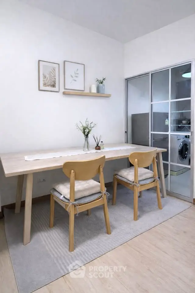 Modern dining area with wooden table and chairs, adjacent to a laundry room.