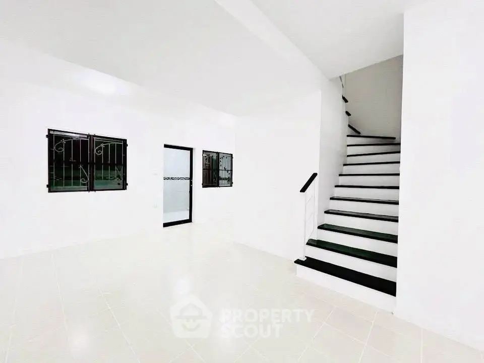 Spacious white interior with modern staircase and tiled flooring, perfect for customization.