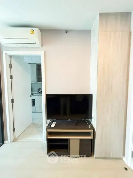 Modern living room with sleek TV setup and air conditioning in a stylish apartment.
