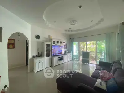 Spacious living room with modern decor and large windows opening to a lush garden view.