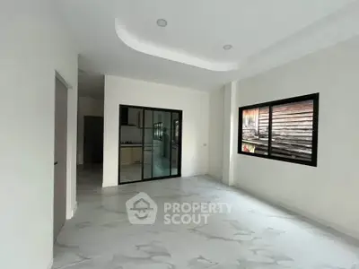 Spacious modern living room with sleek glass doors and large windows for natural light.