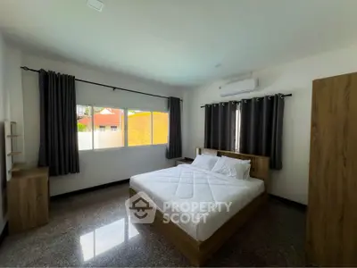 Spacious bedroom with modern furnishings and large window for natural light