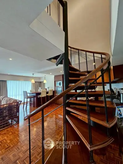 Elegant spiral staircase in modern living room with parquet flooring and open dining area.