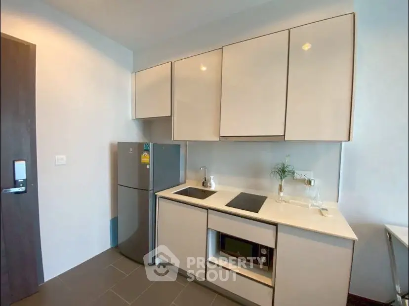 Modern kitchen with sleek cabinets, fridge, and built-in appliances in a compact layout.