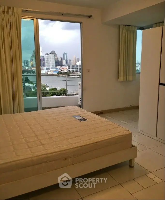 Spacious bedroom with stunning city view and balcony access in modern apartment.