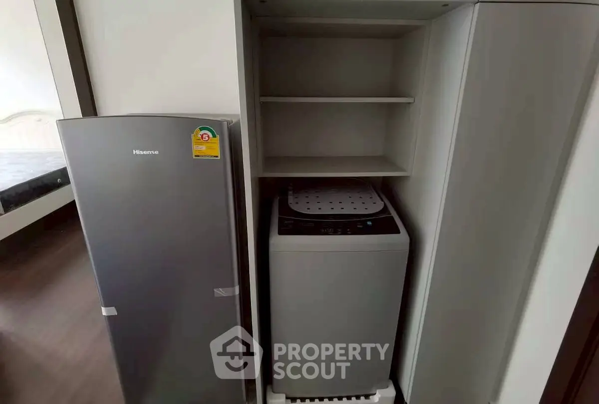 Compact laundry area with washing machine and fridge in modern apartment