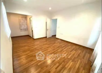 Spacious empty room with wooden flooring and bright natural light, ideal for customization.
