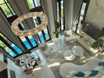 Luxurious living room with high ceilings, elegant chandelier, and pool view.