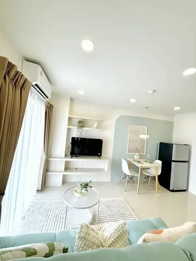 Bright modern living room with stylish decor and dining area, featuring a TV and large window for natural light.