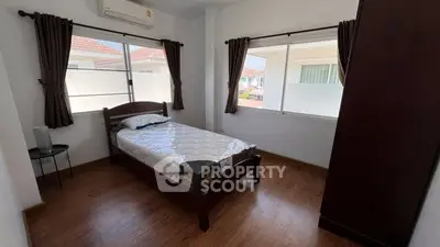 Bright bedroom with wooden flooring and large windows in a modern home.