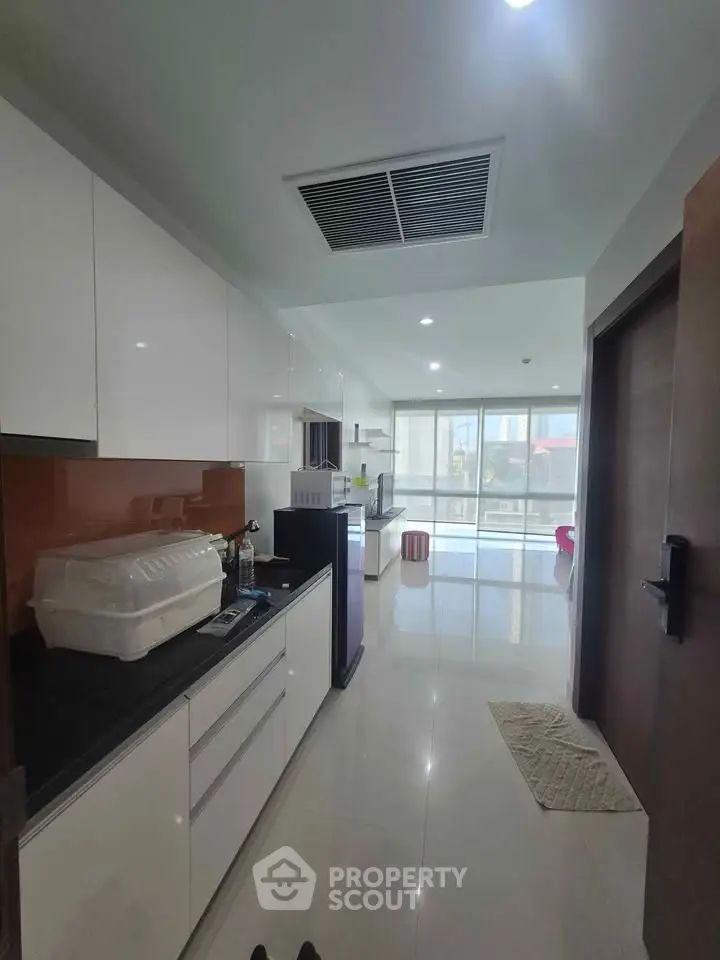 Modern kitchen with sleek cabinetry and open layout leading to bright living area.