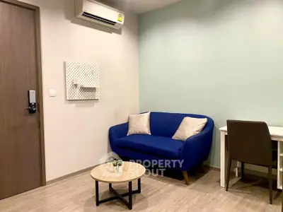 Modern living room with blue sofa, desk, and air conditioning in cozy apartment.