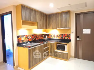 Modern kitchen with stylish cabinetry and colorful backsplash in a cozy apartment.