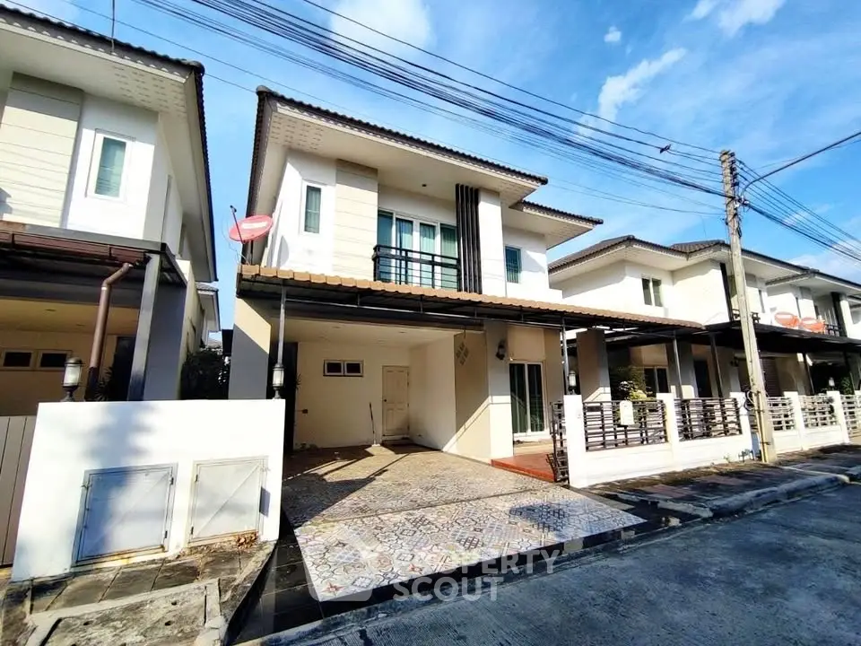 Modern two-story house with tiled driveway and balcony in a suburban neighborhood.