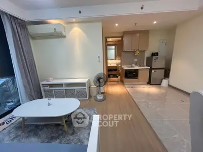 Modern open-layout living room and kitchen with stylish furniture and appliances in a cozy apartment.