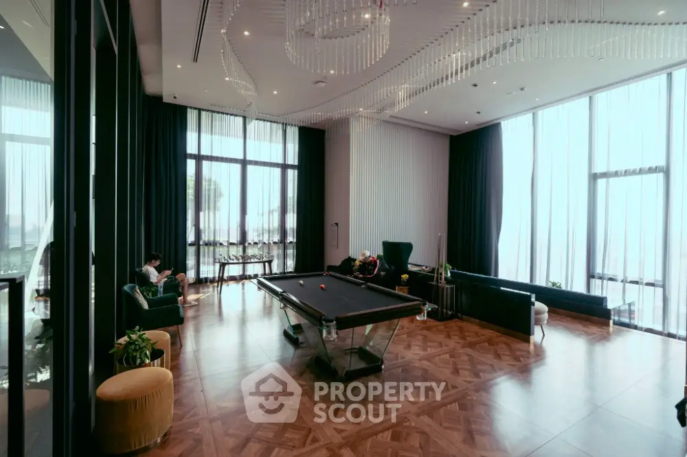 Luxurious living room with pool table and elegant decor, featuring floor-to-ceiling windows and modern lighting.