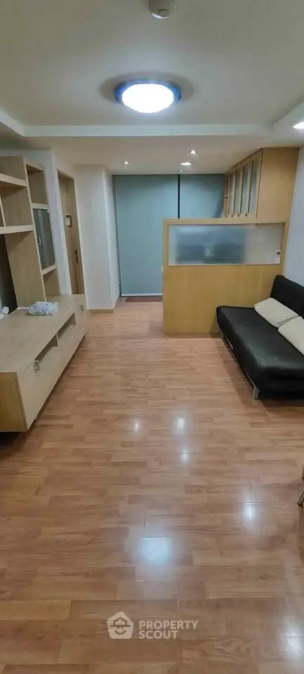 Spacious living room with wooden flooring and modern furniture in a cozy apartment.