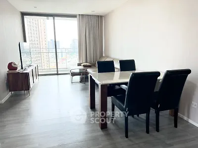 Modern living room with sleek furniture and city view balcony in high-rise apartment.