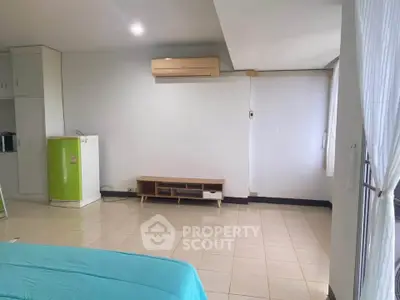 Spacious bedroom with air conditioning and tiled floor, featuring a small kitchenette area.