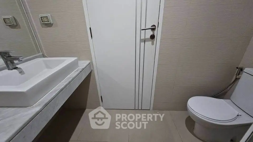 Modern bathroom with sleek sink and toilet in minimalist design.