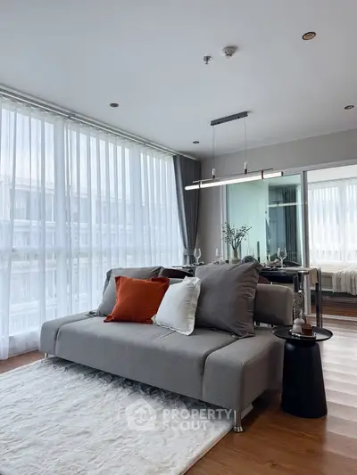 Modern living room with stylish sofa, floor-to-ceiling windows, and elegant decor in a contemporary apartment.