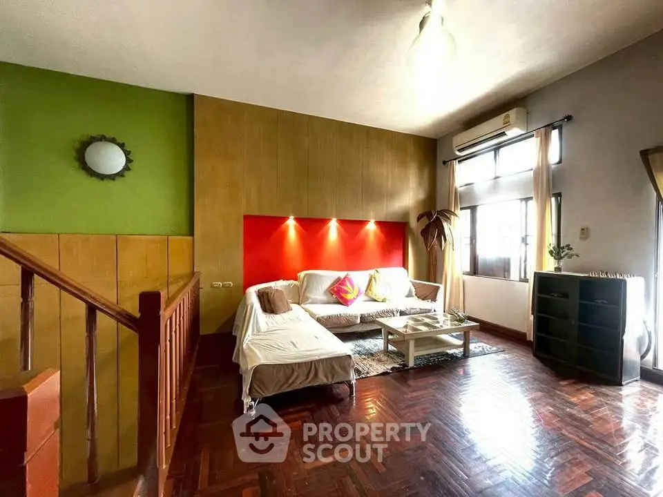 Spacious living room with vibrant accent wall and cozy seating area, perfect for relaxation and entertaining.