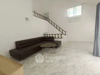 Spacious living room with modern sofa and elegant staircase