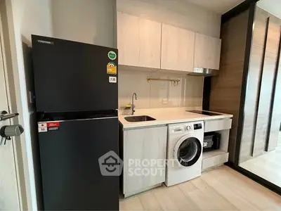 Modern kitchen with sleek appliances and compact design, featuring a washing machine and refrigerator.