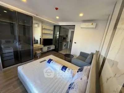 Modern studio apartment with sleek design, featuring a cozy bed, compact living area, and in-unit washing machine.