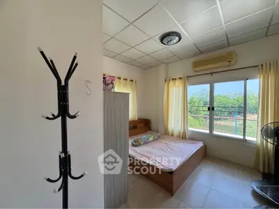 Bright bedroom with large window and scenic view, featuring modern furniture and air conditioning.
