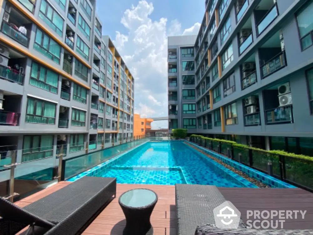 Modern apartment complex with a stunning outdoor pool and sun loungers, perfect for relaxation and leisure.