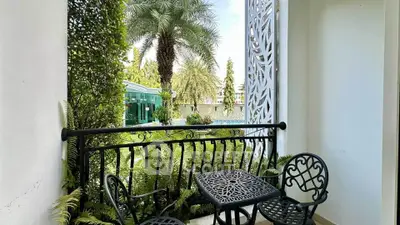 Charming balcony with elegant wrought iron furniture overlooking lush garden and palm trees.