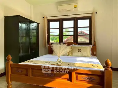 Cozy bedroom with wooden bed frame, large window, and air conditioning unit, offering a serene and inviting atmosphere.