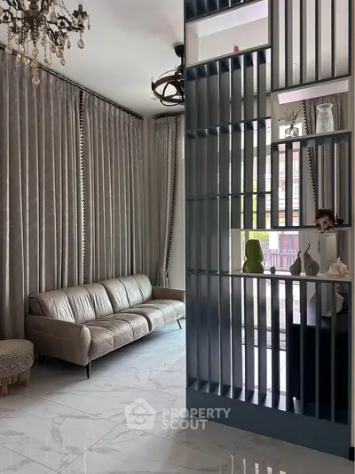 Elegant living room with modern decor and stylish partition, featuring a plush sofa and floor-to-ceiling curtains.