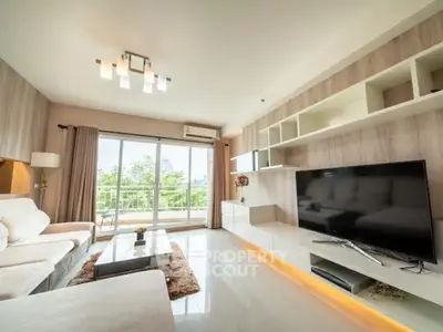 Spacious modern living room with large TV and balcony view