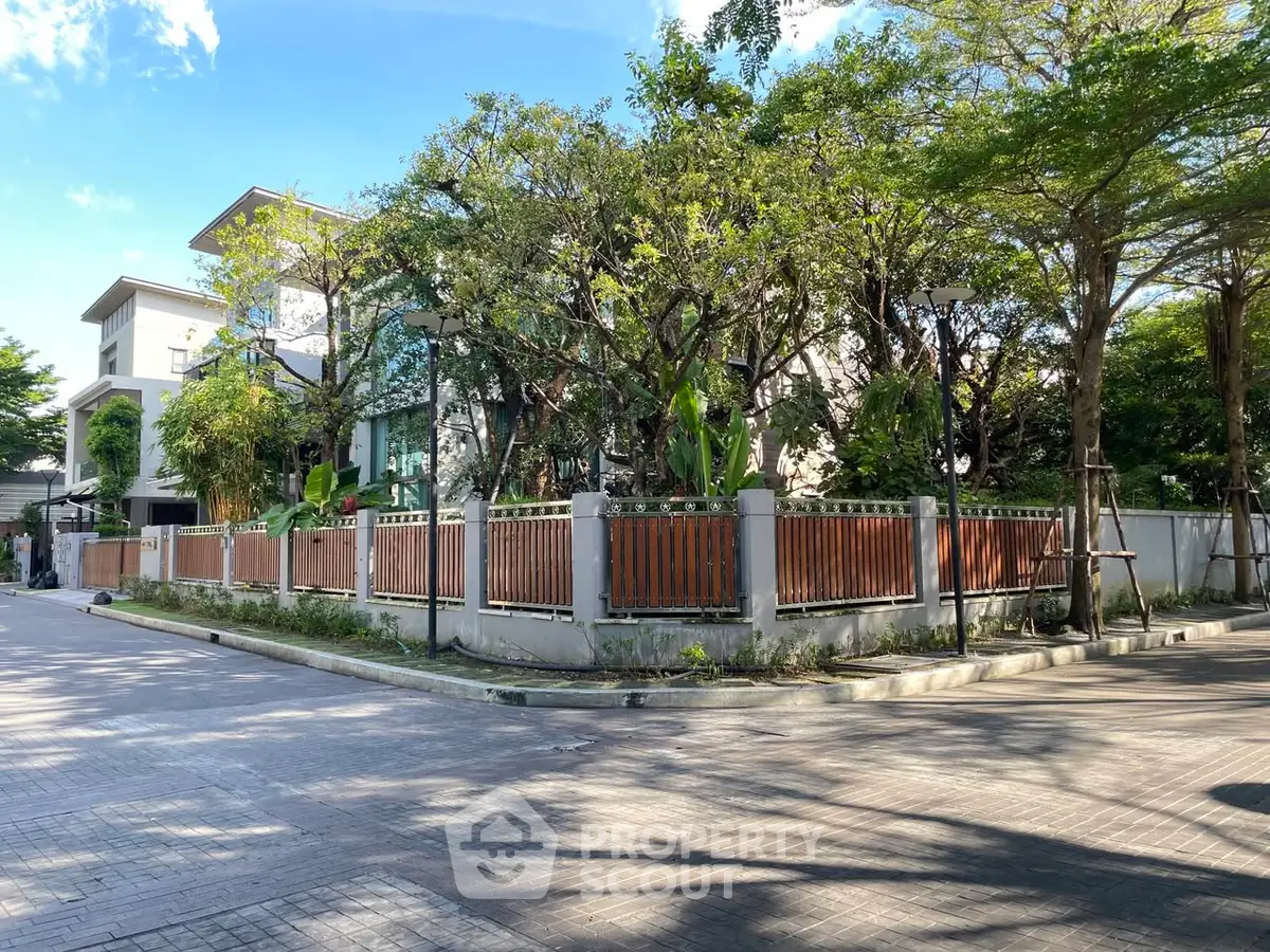 Luxurious modern home with lush garden and elegant fence in serene neighborhood.