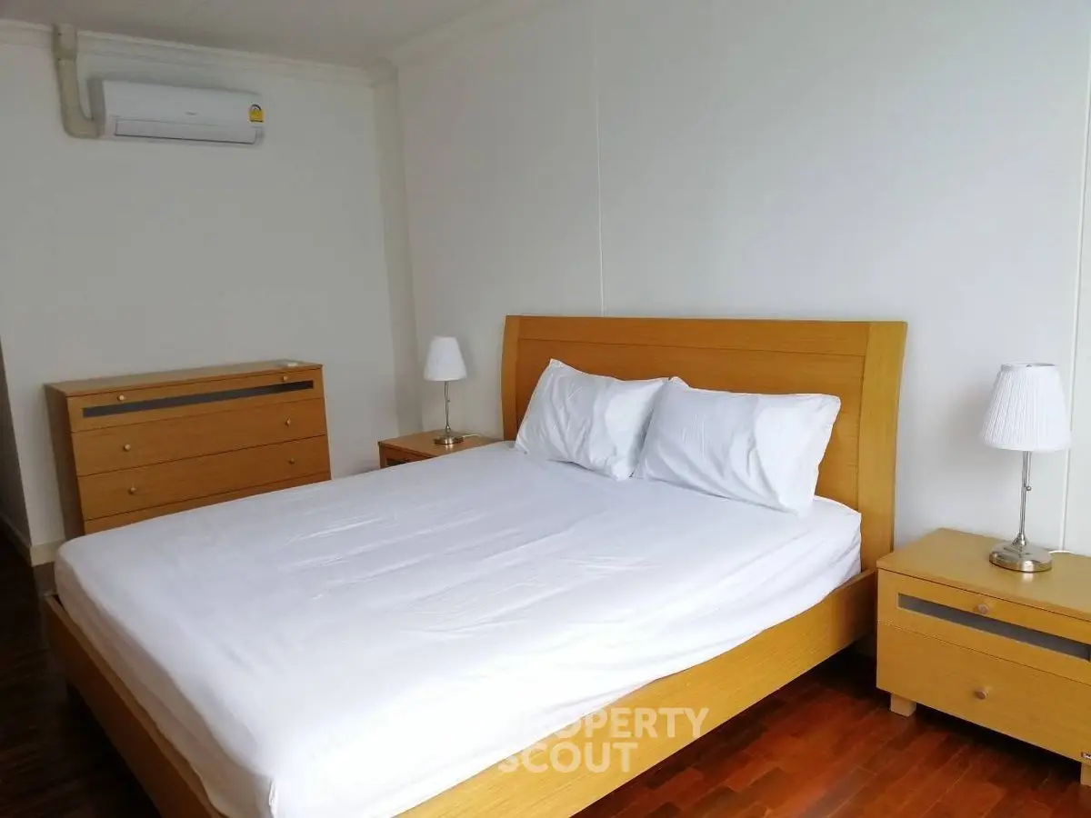 Spacious bedroom with modern wooden furniture and air conditioning