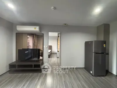 Modern living room with sleek flooring, TV setup, and visible bedroom entry.