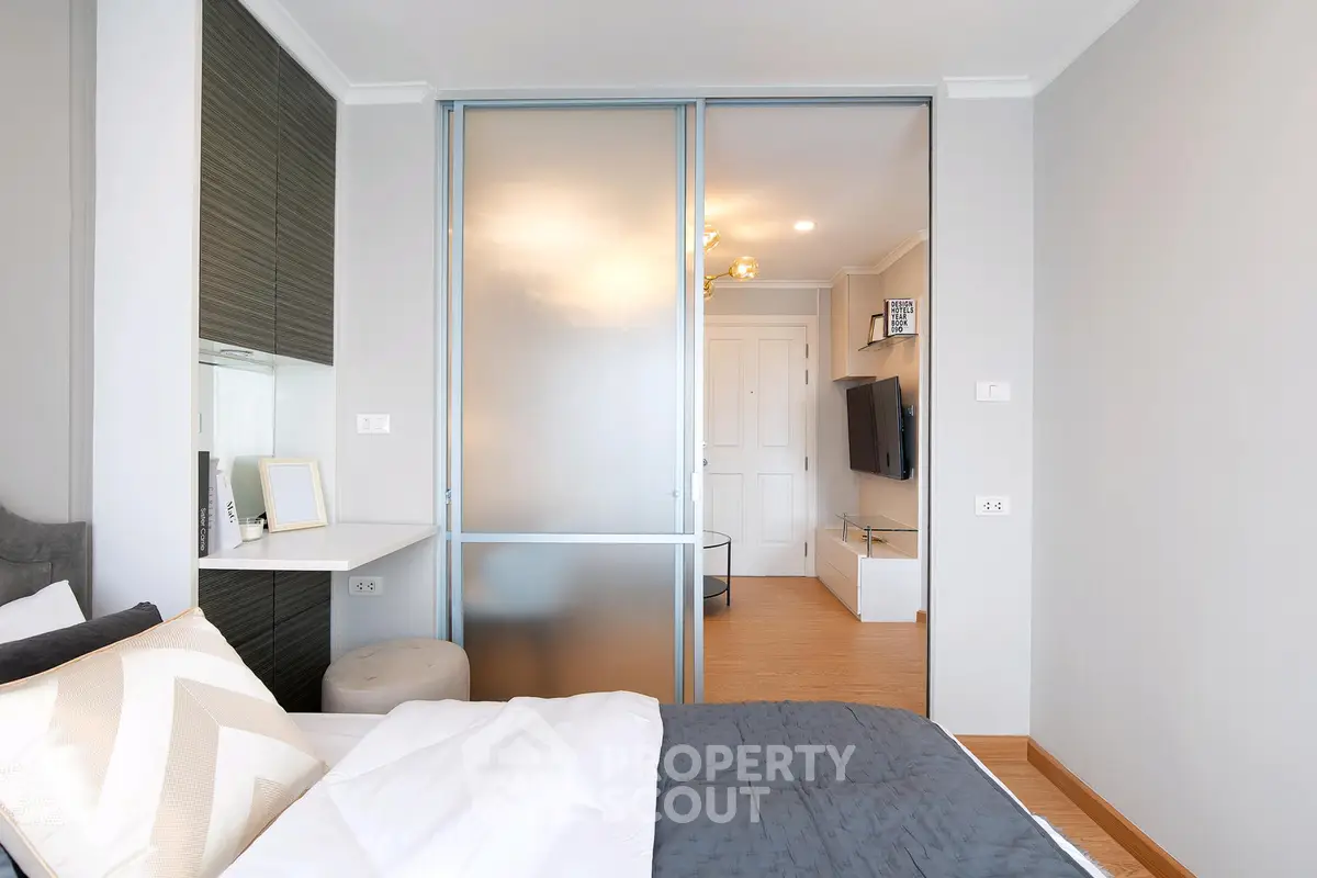 Modern bedroom with sliding glass doors leading to a stylish living area.