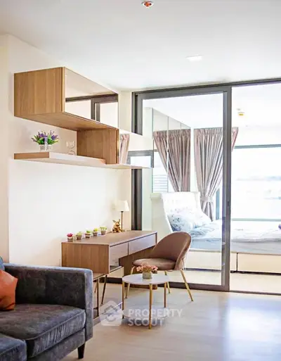 Modern living room with stylish furniture and large windows leading to a cozy bedroom.