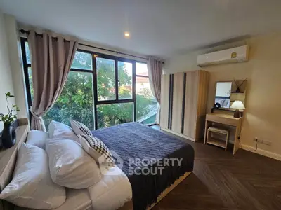 Spacious bedroom with large window and modern decor, featuring a cozy bed and stylish furniture.