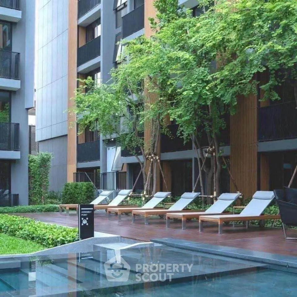 Modern apartment complex with lush greenery and inviting poolside area.