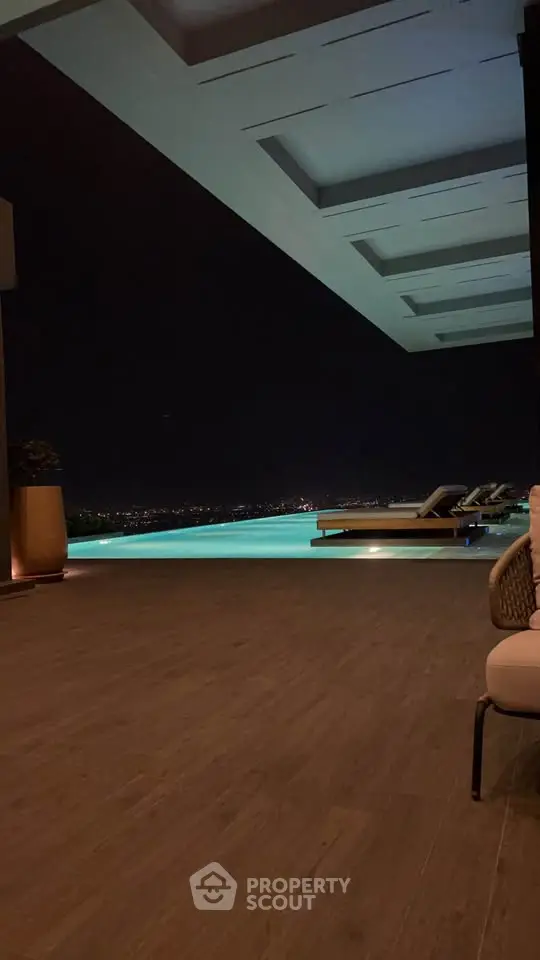 Luxurious rooftop pool with stunning night city view and elegant lounge chairs.